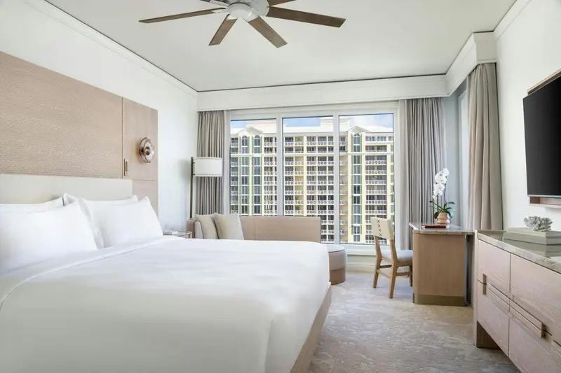 Une chambre lumineuse avec un grand lit et une vue sur un bâtiment.