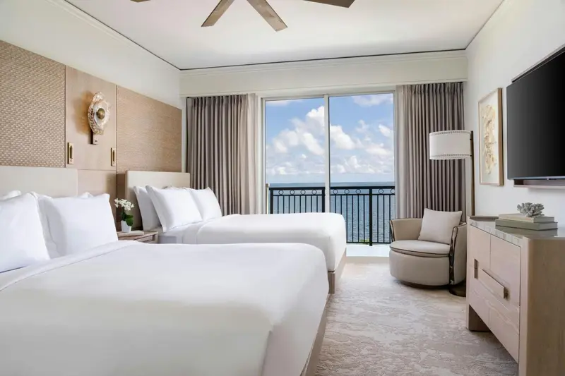 Chambre lumineuse avec deux lits et vue sur la mer.