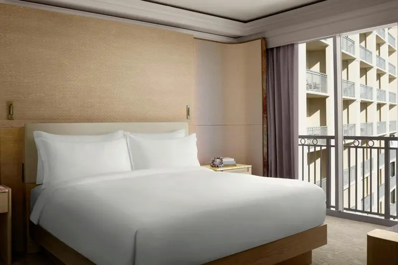 Une chambre lumineuse avec un grand lit et un balcon offrant une vue sur la mer.