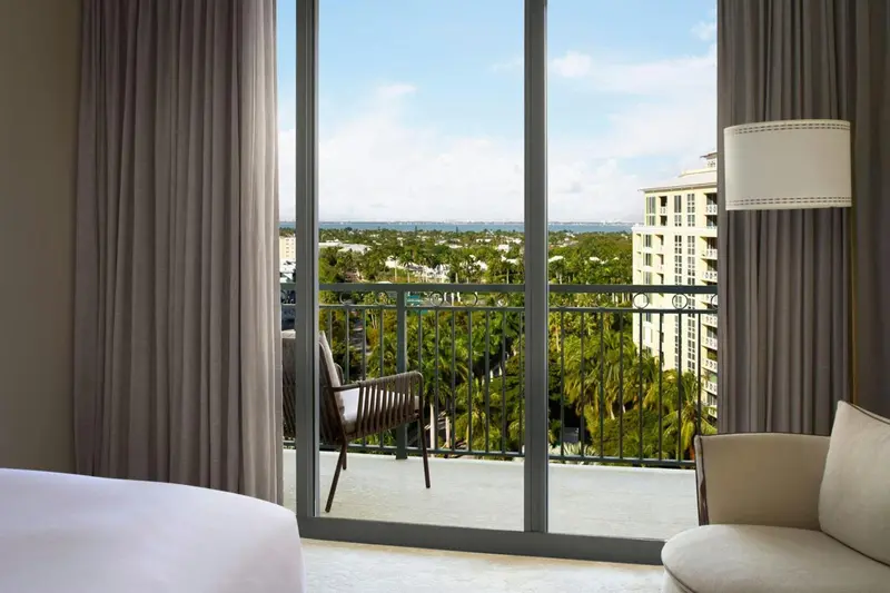 Vue sur la végétation et les bâtiments depuis une chambre avec balcon.
