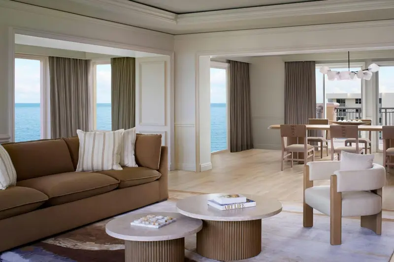 Espace de vie lumineux avec canapé, table basse et vue sur la mer.