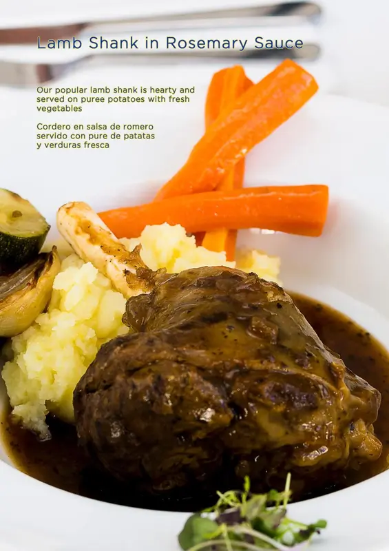 Un plat de jarret d'agneau en sauce au romarin, accompagné de purée de pommes de terre et de légumes.