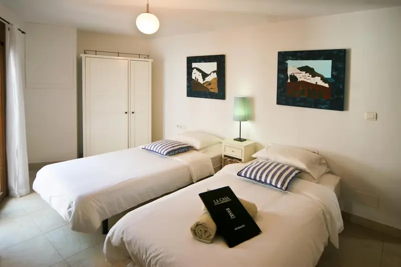 Une chambre lumineuse avec deux lits simples et des tableaux décoratifs.