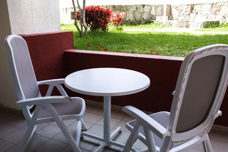 Mobilier d'extérieur blanc sur une terrasse carrelée.