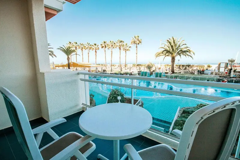 Une terrasse avec table et chaises offre une vue sur une piscine et la mer.