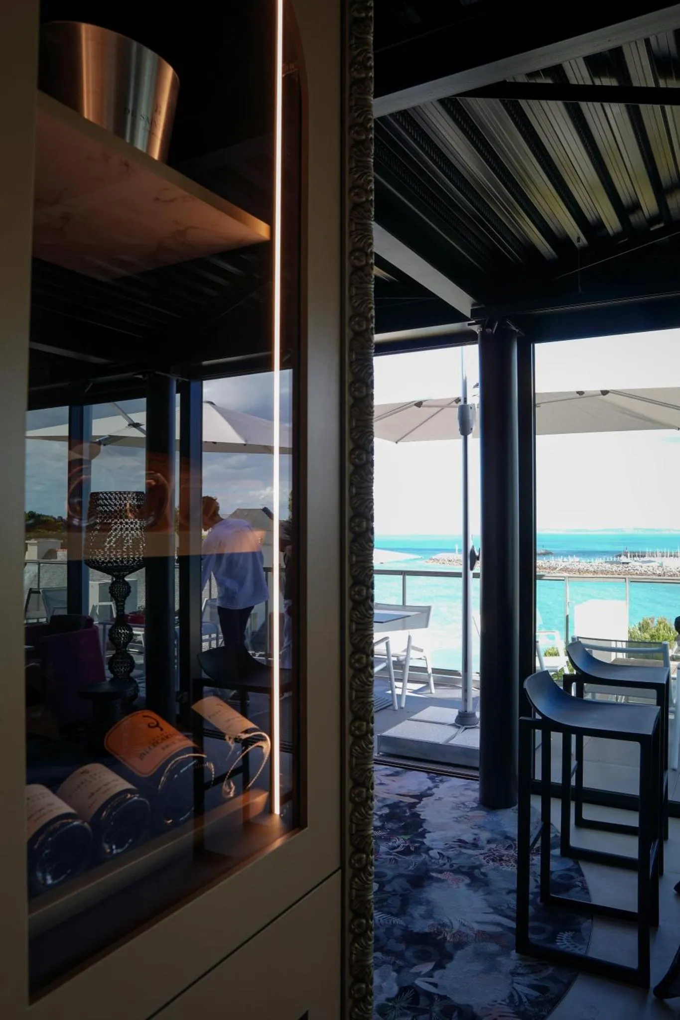 Terrasse ombragée avec mobilier d'extérieur et vue sur la mer.