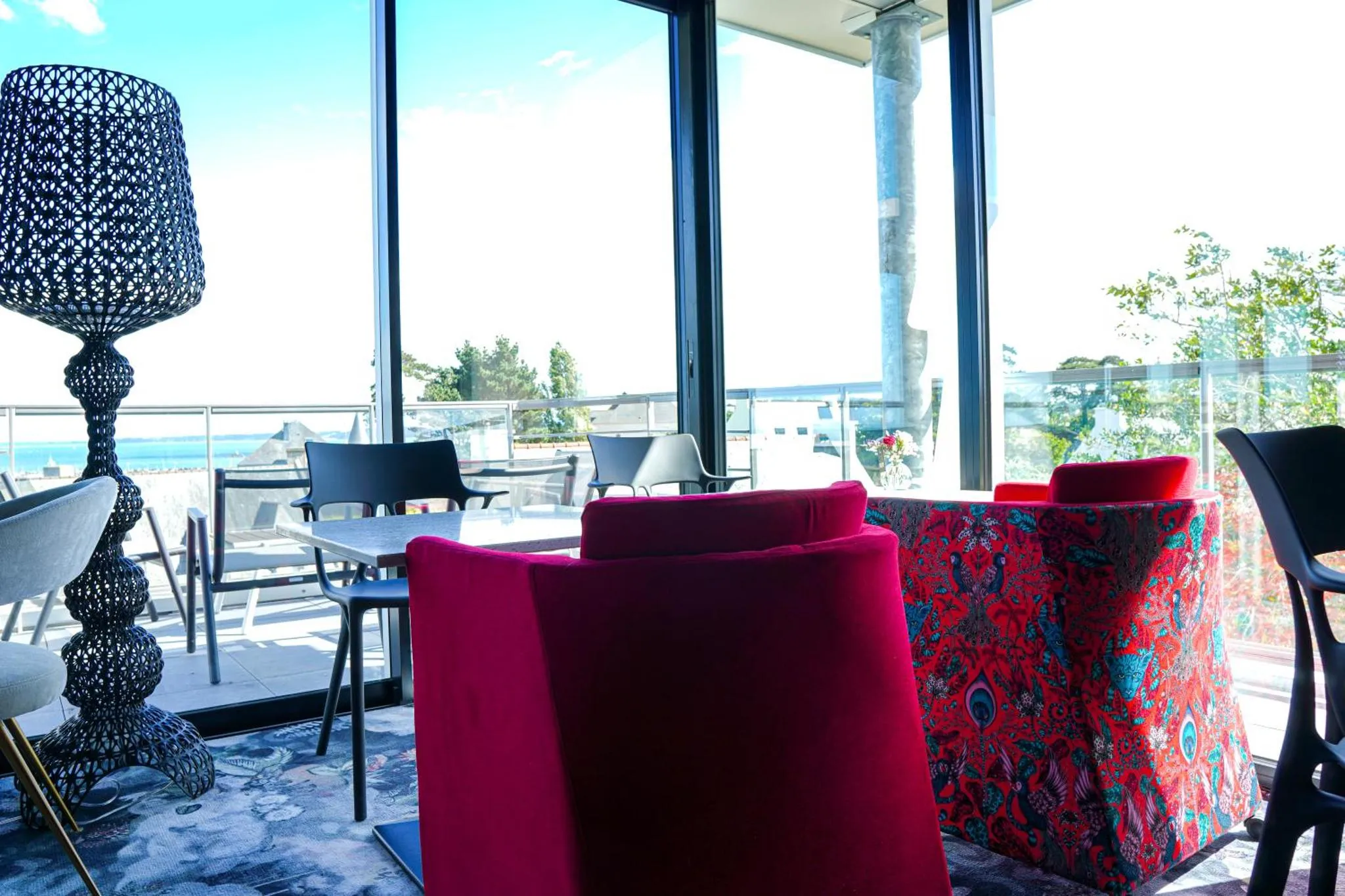 Espace de détente intérieur avec mobilier coloré et vue sur la mer.