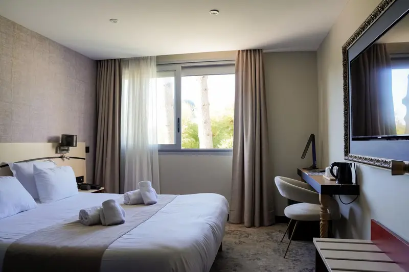 Une chambre lumineuse avec un lit fait et une vue sur la végétation.