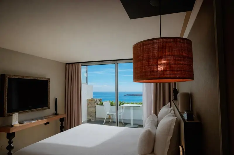 Chambre lumineuse avec un grand lit et vue sur la mer.