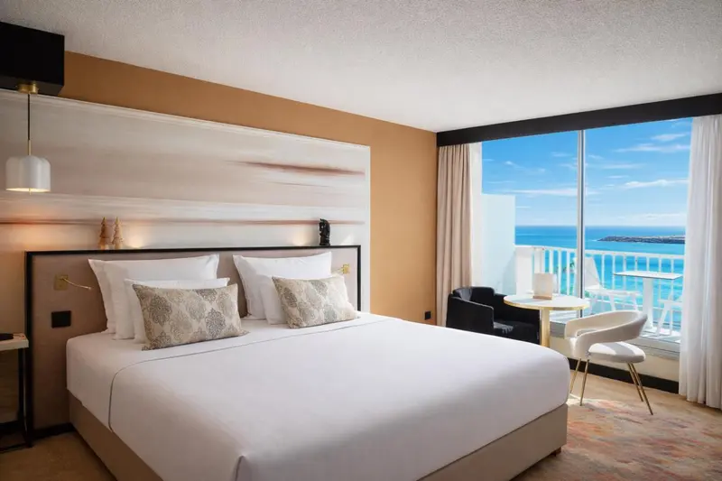 Une chambre lumineuse avec un grand lit et une vue sur la mer.