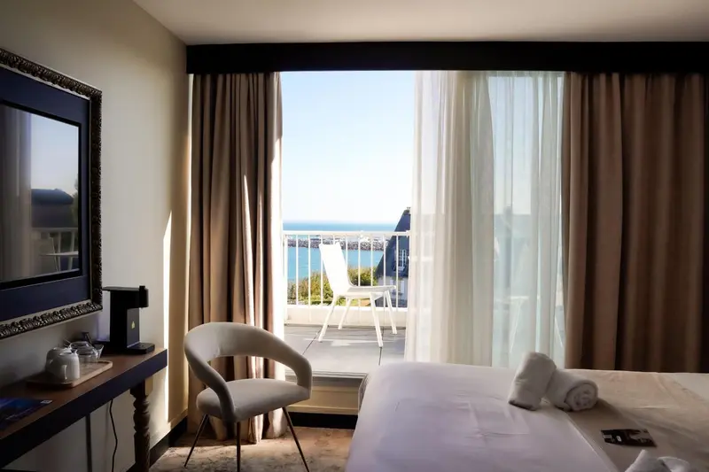 Une chambre lumineuse avec vue sur la mer depuis un balcon.