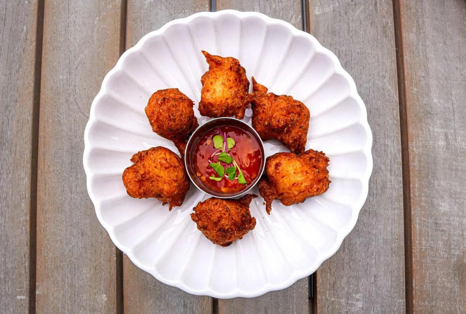Assiette de beignets de poisson servis avec une sauce rouge.