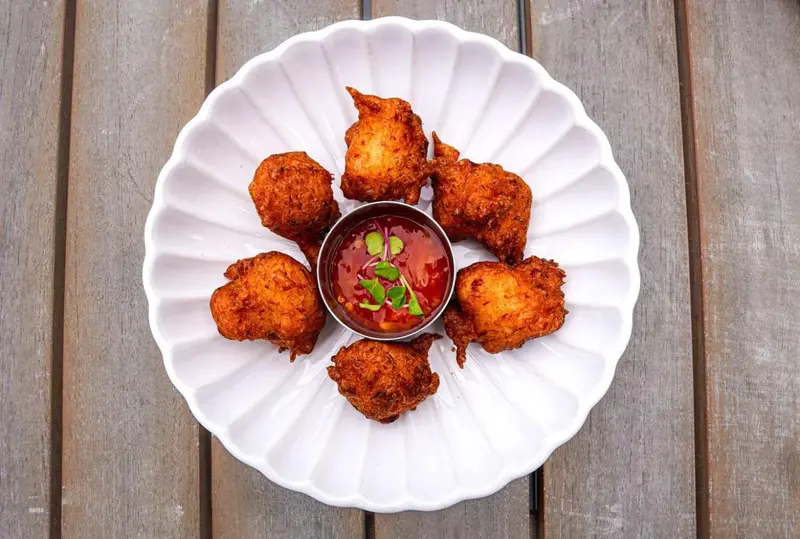 Assiette de beignets de poisson servis avec une sauce rouge.