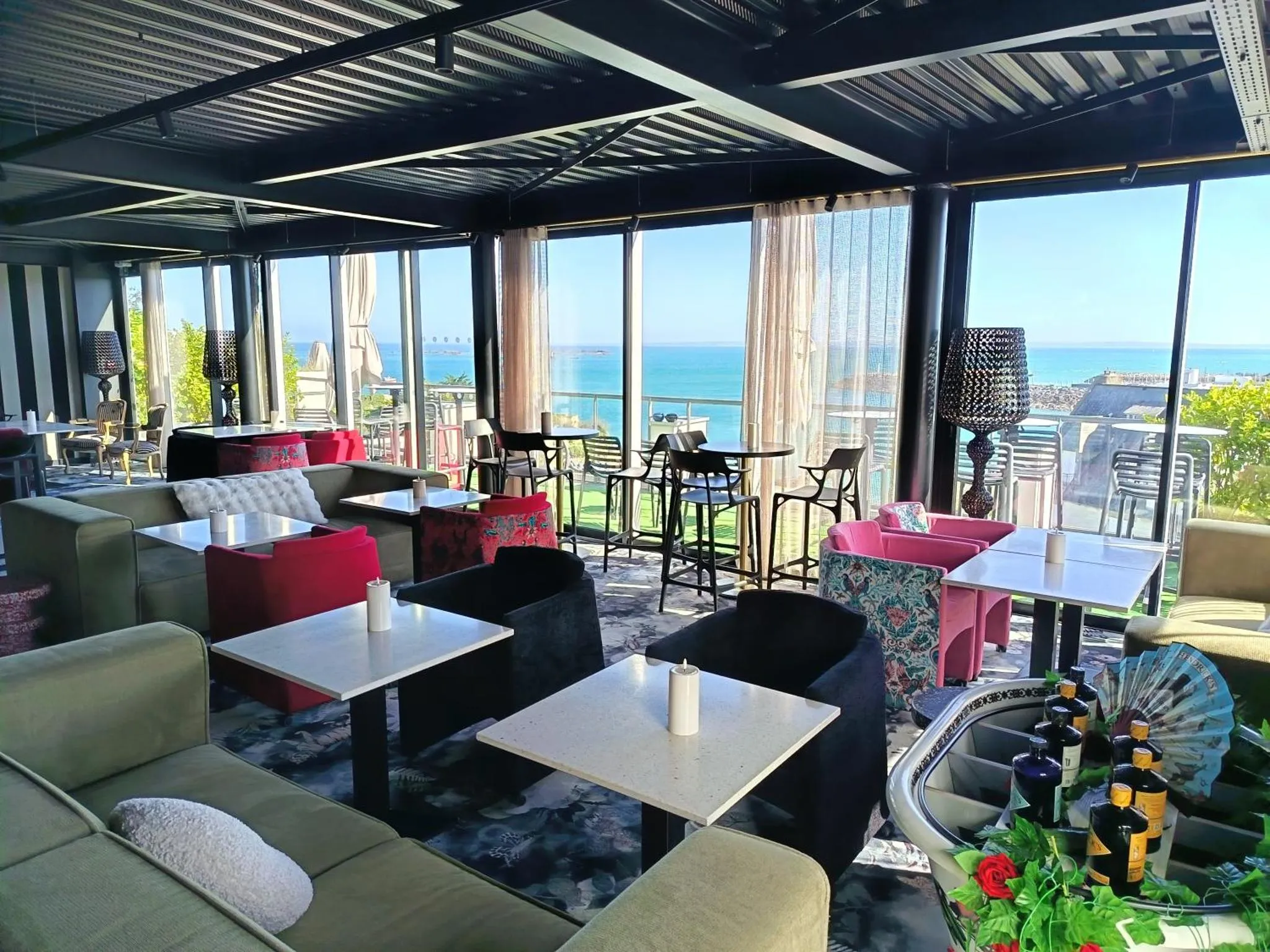 Un espace de détente intérieur avec des canapés, des tables basses et une vue sur la mer.