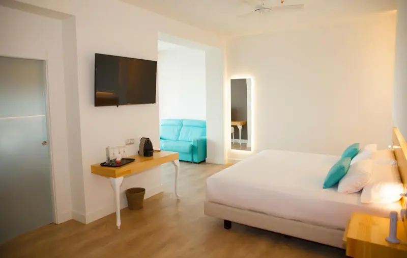 Une chambre lumineuse avec un canapé turquoise et un grand lit.