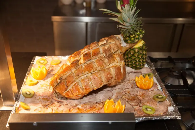 Une piece de viande grillee, decoree de fruits, est presentee sur un plateau.