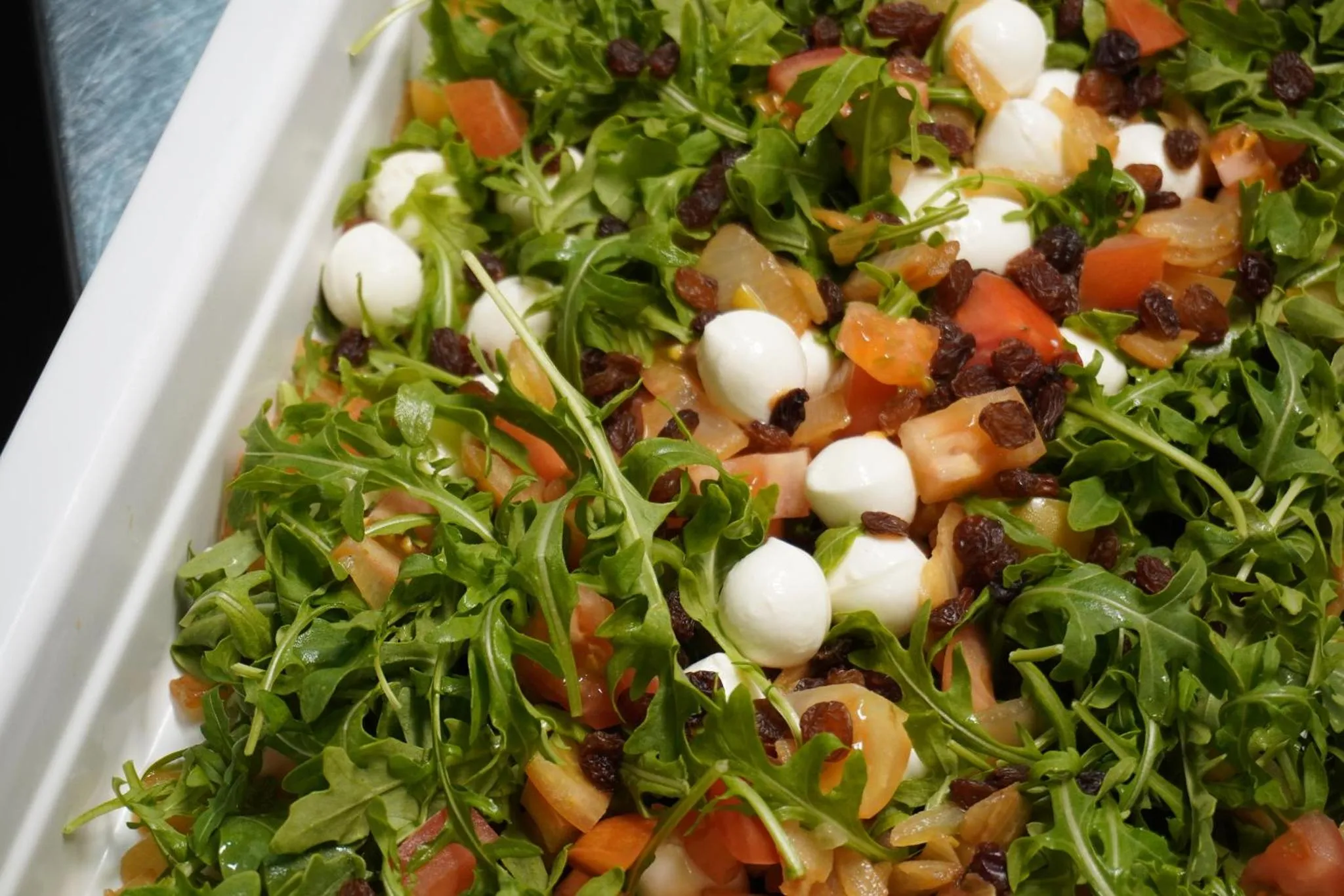 Salade composée de roquette, tomates, mozzarella et raisins secs.