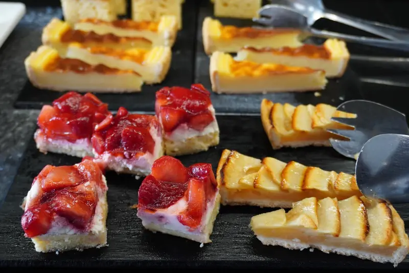 Assortiment de pâtisseries aux fruits présentées sur un plateau noir.
