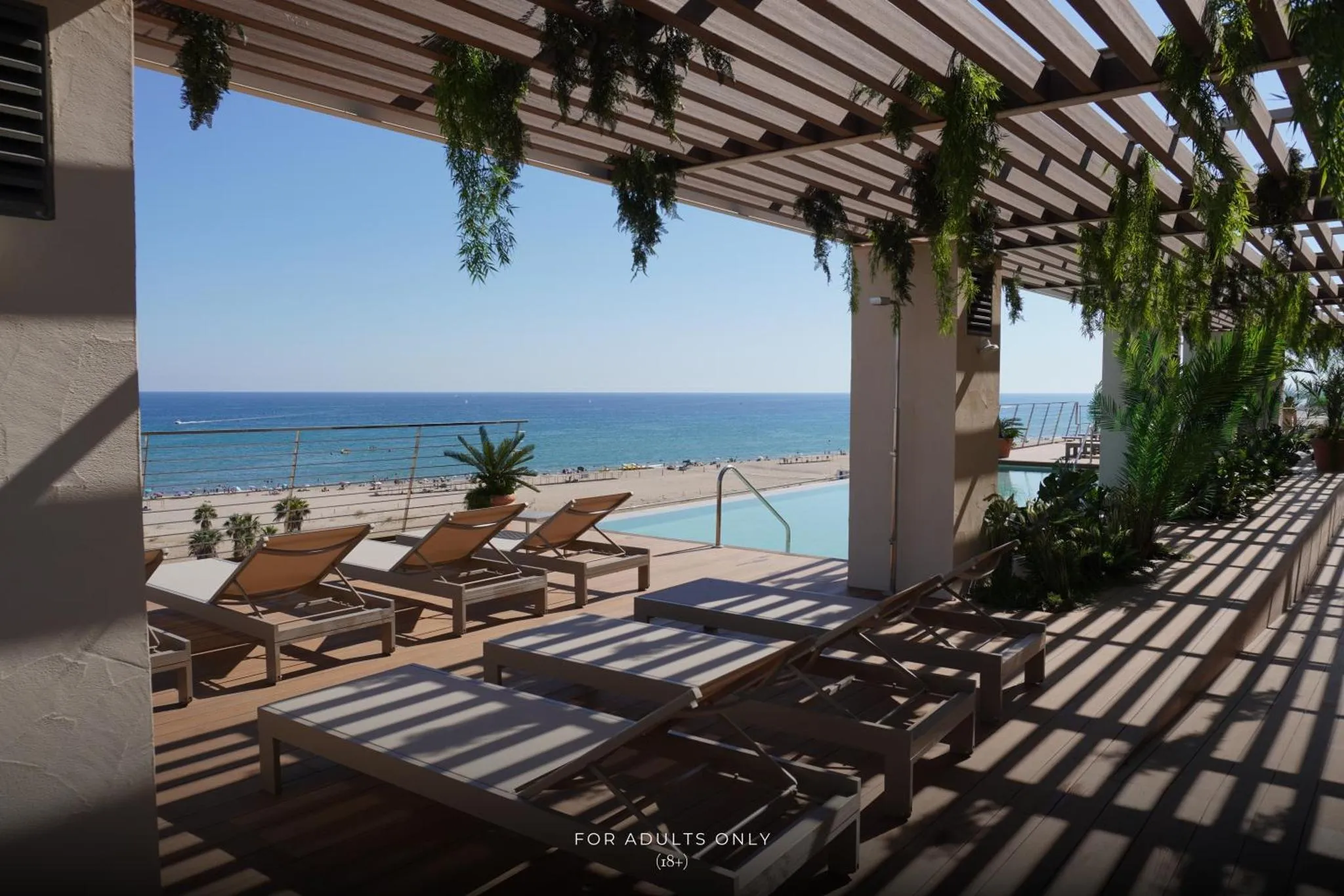 Terrasse avec transats et piscine donnant sur la mer.