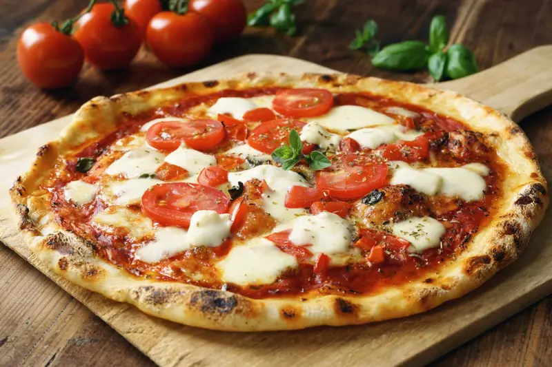 Une pizza à la tomate et à la mozzarella est présentée sur une planche en bois.