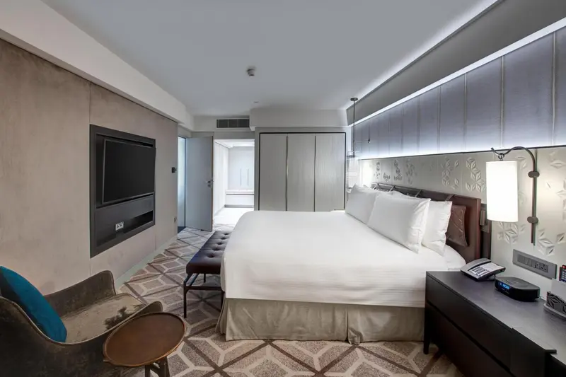 Chambre lumineuse avec un grand lit et un fauteuil.