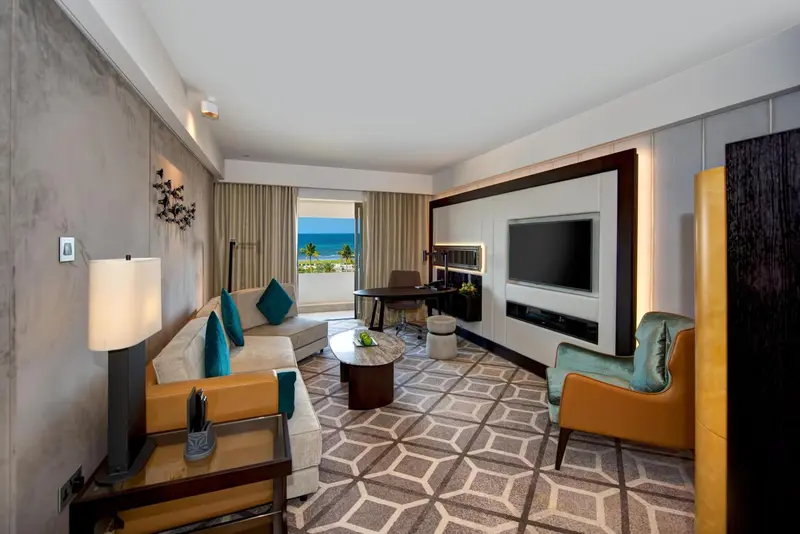Espace de séjour lumineux avec canapé, fauteuils et vue sur la mer.