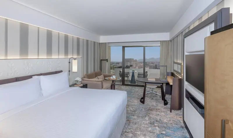 Chambre lumineuse avec un grand lit et un accès à un balcon.