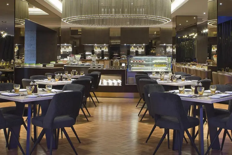 Une salle de restaurant lumineuse avec des tables dressées et un buffet.