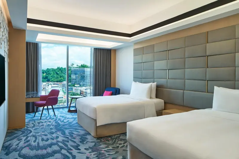 Chambre moderne avec deux lits simples et une vue sur la ville.