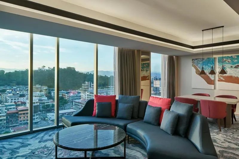 Un salon moderne avec un canapé d'angle et une vue sur la ville.