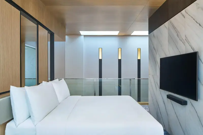 Une chambre lumineuse avec un grand lit et un téléviseur mural.