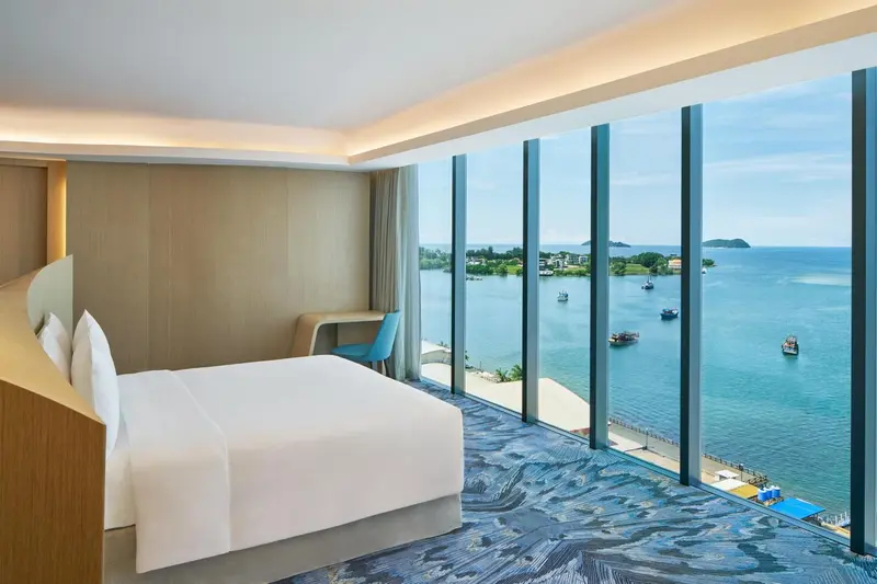 Chambre lumineuse avec un grand lit et vue sur la mer.