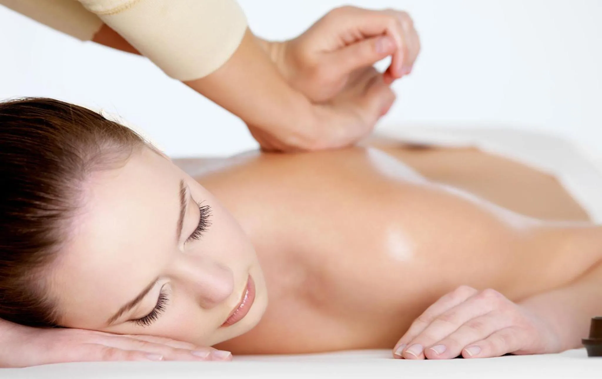 Une femme allongée reçoit un massage du dos.