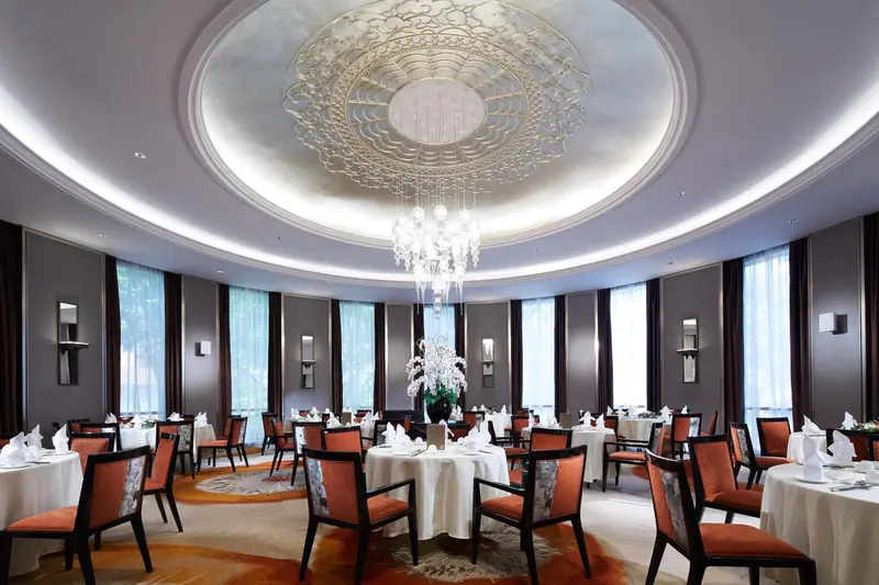 Une salle lumineuse avec des tables dressées pour un repas.