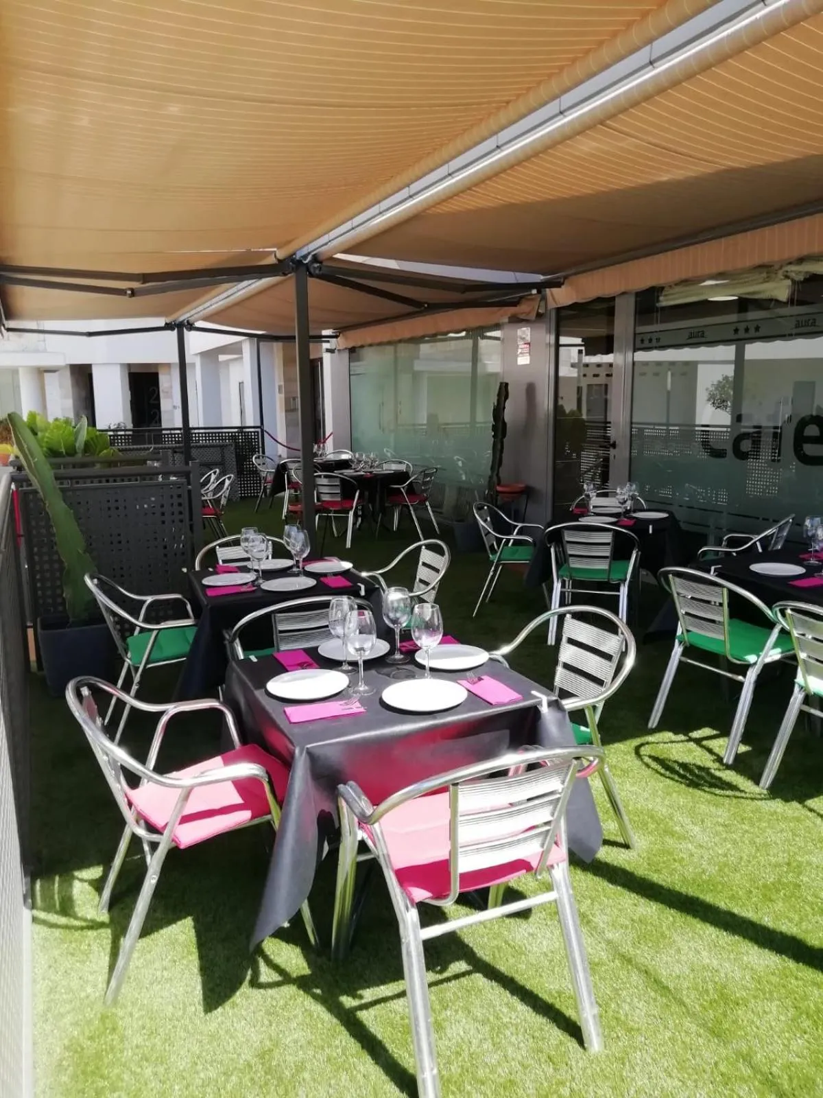 Tables dressées sur une terrasse ombragée avec une vue sur un bâtiment.