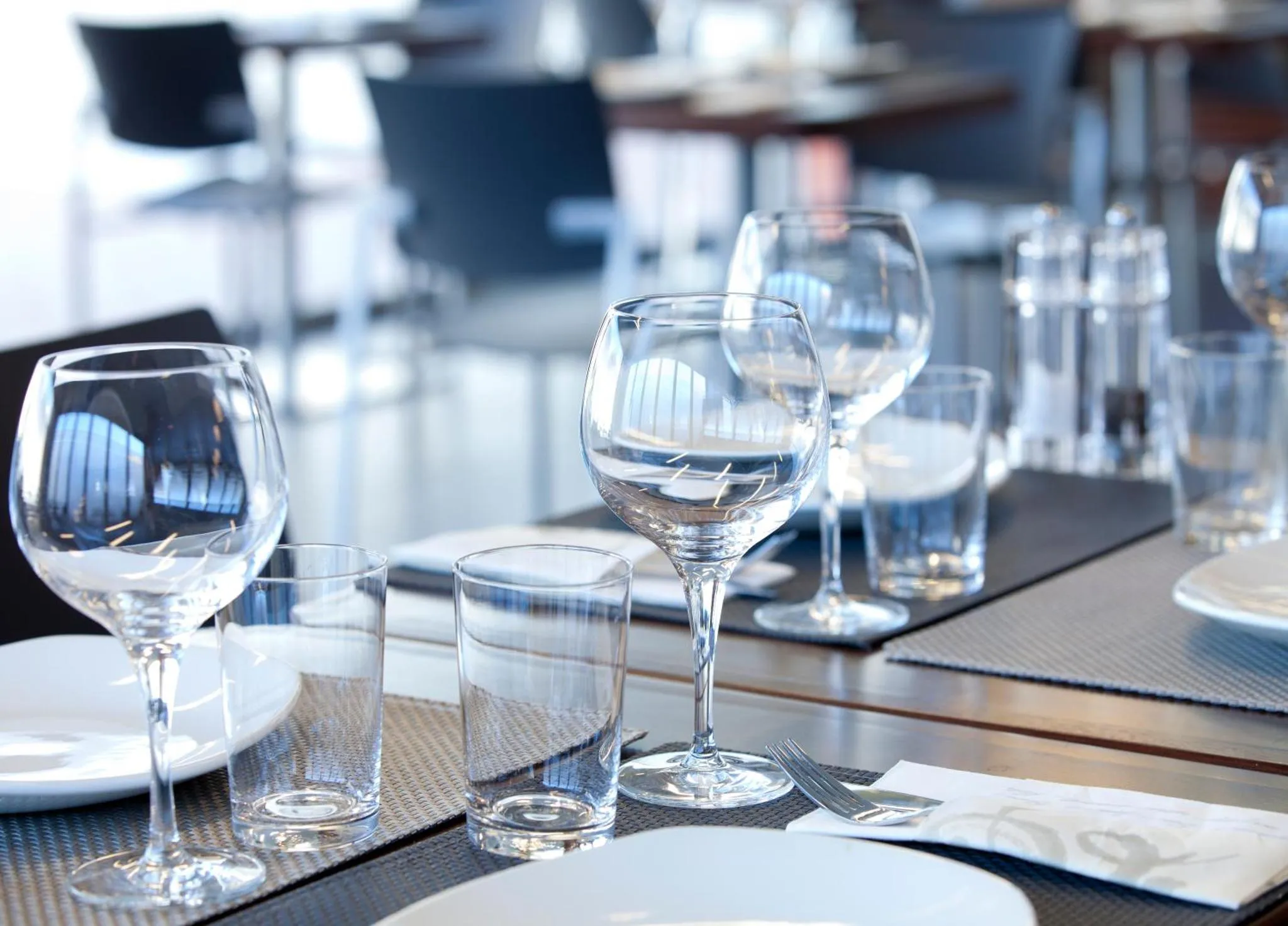 Une table est dressée avec des verres et de la vaisselle.