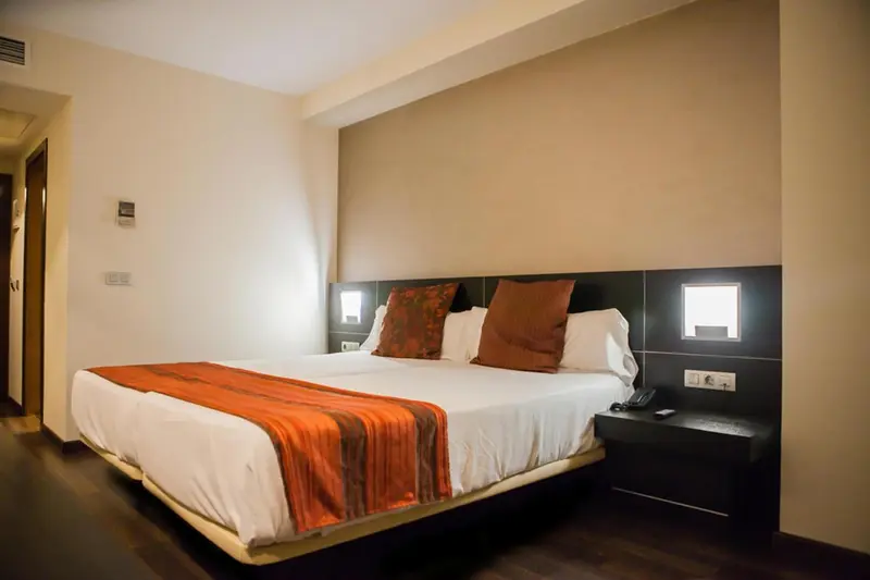 Une chambre avec un grand lit recouvert d'une courtepointe orange et de coussins décoratifs.