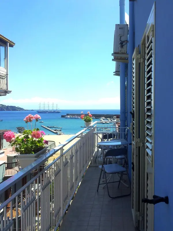 Balcon fleuri avec vue sur la mer et un port.