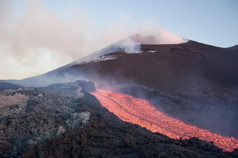 Un écoulement de lave rouge descend le flanc d'un volcan en éruption.