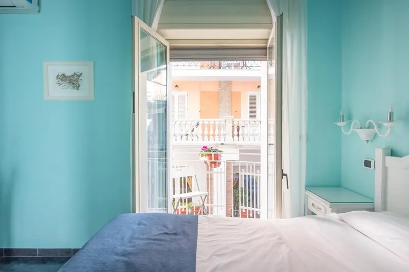 Une chambre lumineuse s'ouvre sur un balcon fleuri.