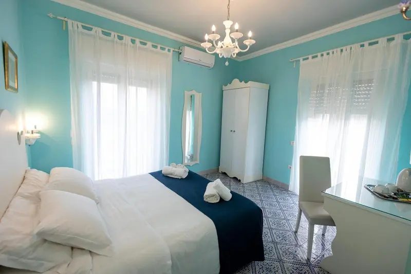 Une chambre lumineuse avec un grand lit recouvert d'une courtepointe bleue et de coussins blancs.