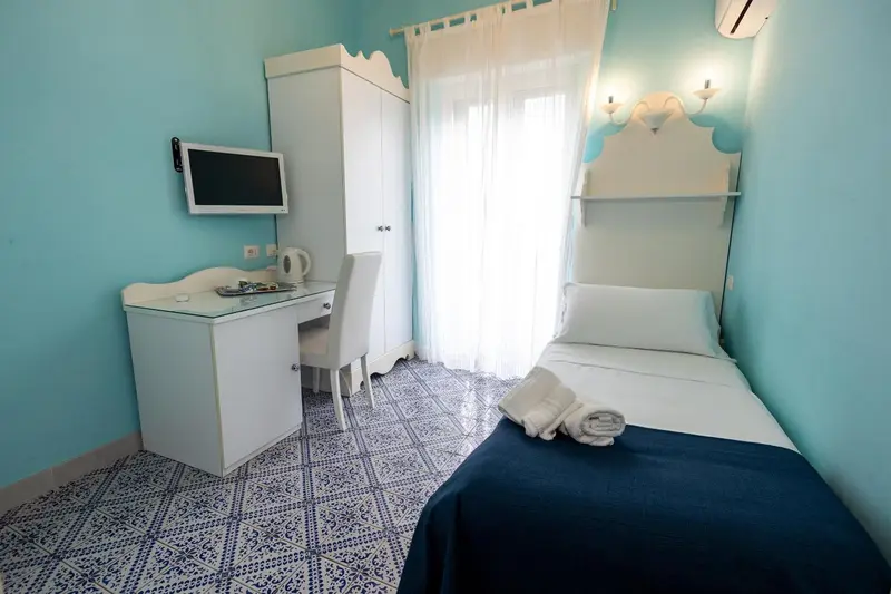 Une chambre lumineuse avec un lit simple et un bureau.