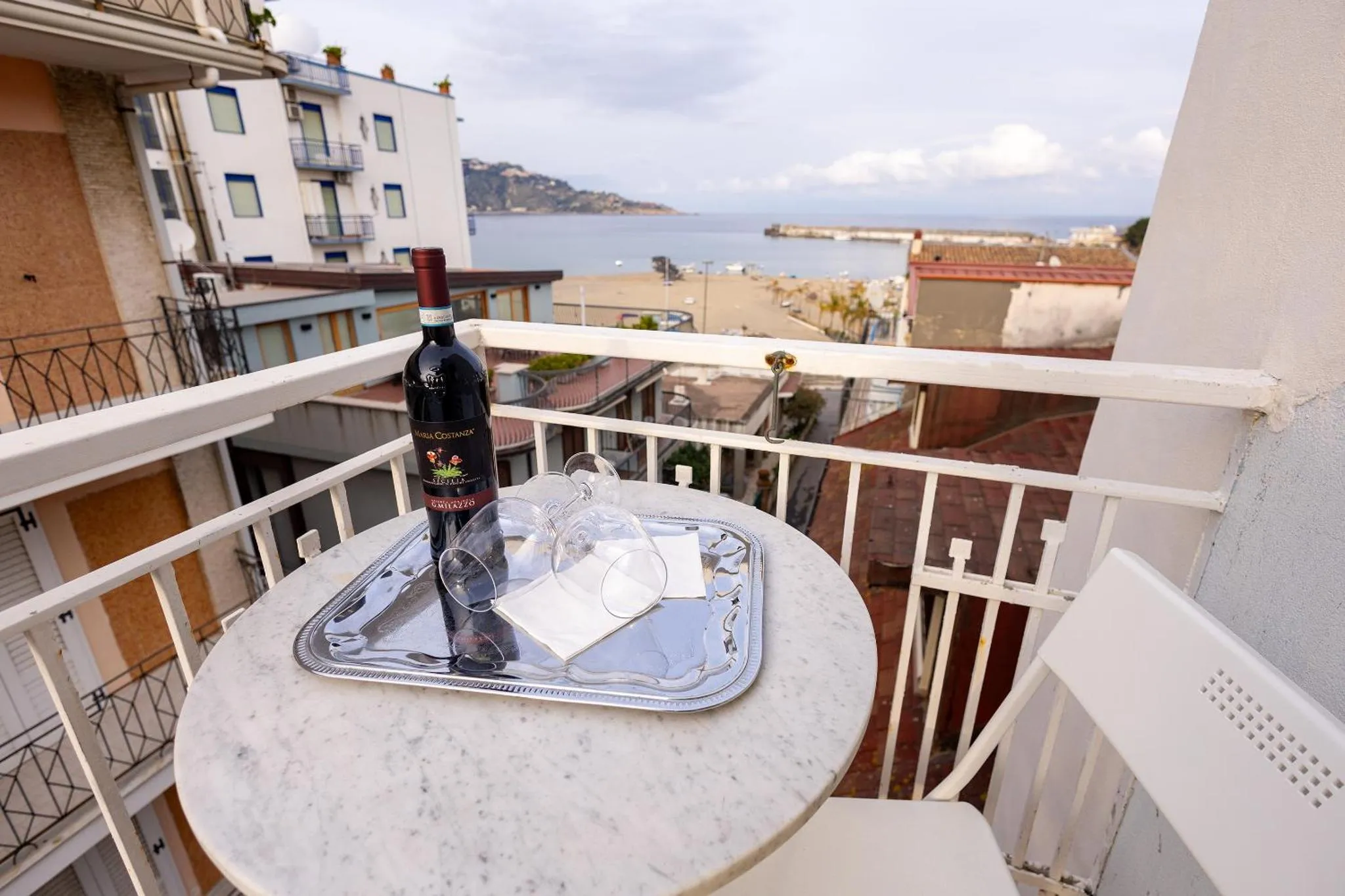 Une table ronde avec une bouteille de vin et des verres sur un balcon.