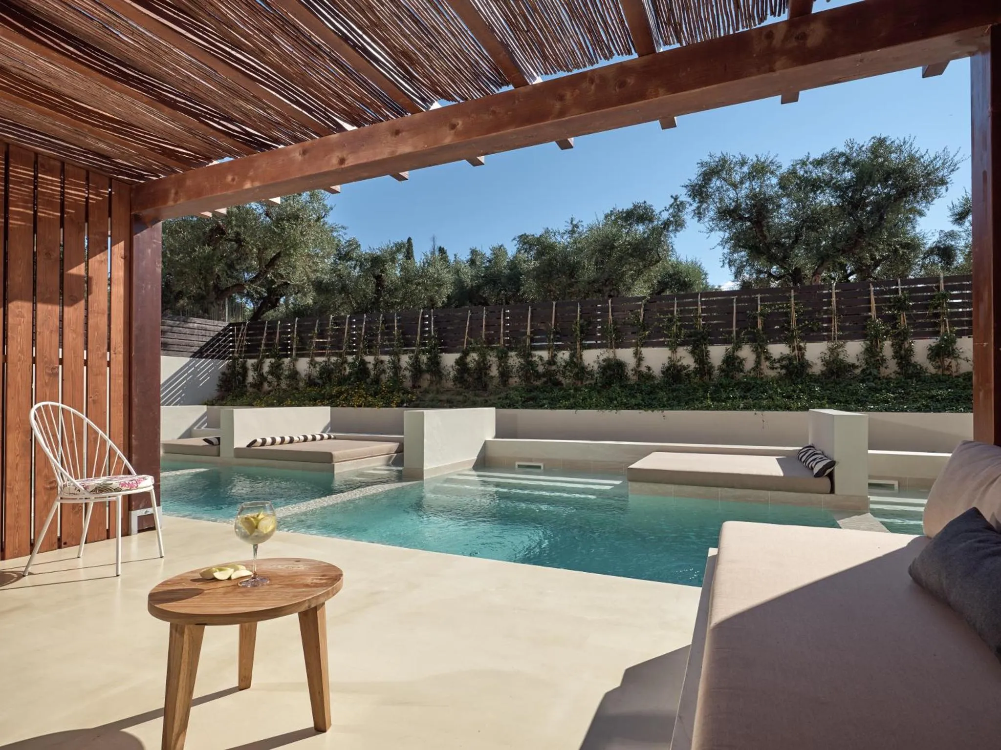 Une terrasse ombragée donne sur une piscine et un jardin verdoyant.
