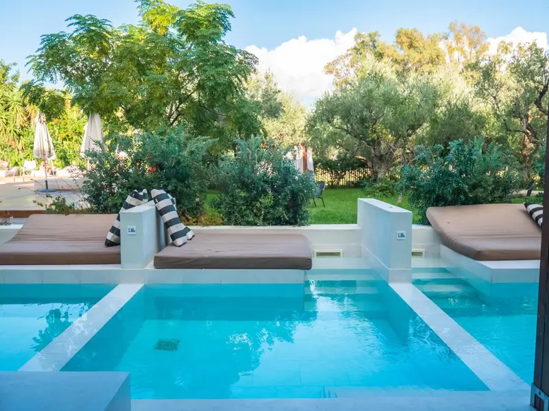 Transats et piscine au bord d'un jardin luxuriant.