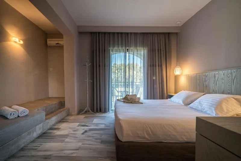 Une chambre lumineuse avec un grand lit et un accès à une terrasse.