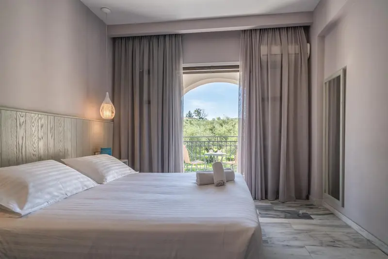 Une chambre lumineuse avec un grand lit et un balcon.