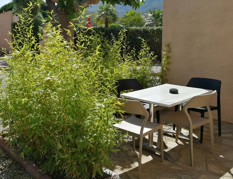 Une table et des chaises en plastique sont placées sur une terrasse ensoleillée.