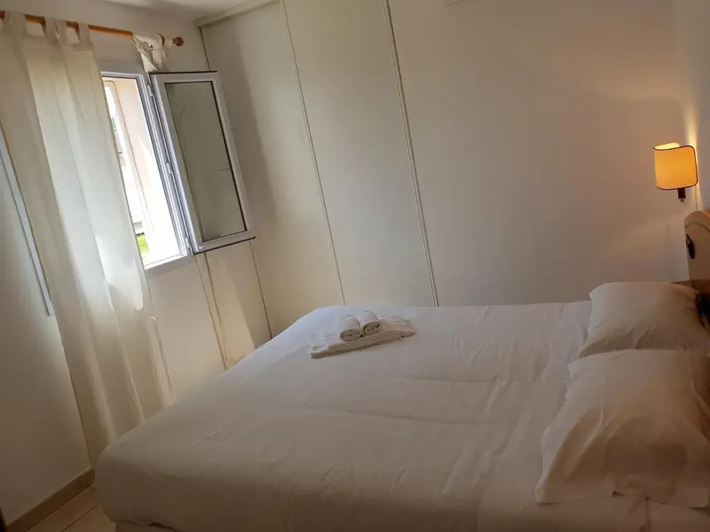 Une chambre lumineuse avec un lit fait et une fenêtre.