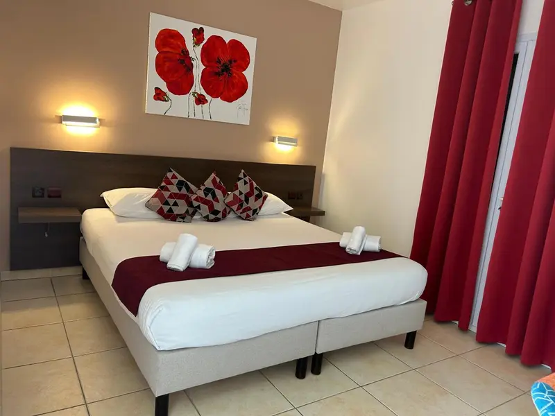 Une chambre avec un grand lit recouvert d'une courtepointe blanche et de coussins.